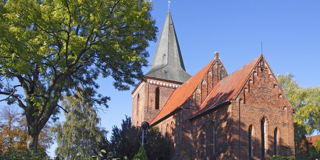 Eine Kirche aus roten Backsteinen, im Vordergrund steht ein Baum Eine Kirche aus roten Backsteinen, im Vordergrund steht ein Baum