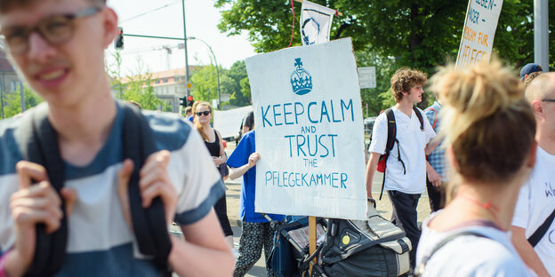 Eine Teilnehmerin hält auf einer Demonstration für bessere Arbeitsbedingungen in der Pflegebranche ein Schild mit der Aufschrift "Keep Calm and Trust the Pflegekammer". Eine Teilnehmerin hält auf einer Demonstration für bessere Arbeitsbedingungen in der Pflegebranche ein Schild mit der Aufschrift "Keep Calm and Trust the Pflegekammer".