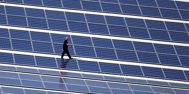 Jemand läuft zwischen Solarpaneelen Jemand läuft zwischen Solarpaneelen