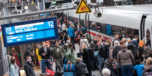 Wartende drängen sich auf einem Bahnhof um den Eingang eines Zuges