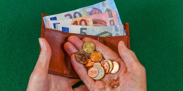 Geldbörse mit Scheinen und eine Hand mit Kleingeld Geldbörse mit Scheinen und eine Hand mit Kleingeld