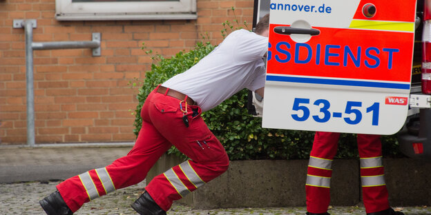 Retter schiebt Trage in den Rettungswagen