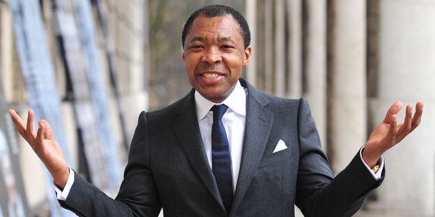 Okwui Enwezor hebt beide Arme