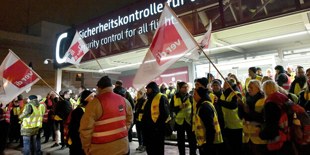 Streikendes Sicherheitspersonal steht vor der Sicherheitskontrolle