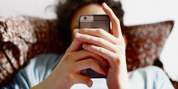 Eine liegende Person mit einem Smartphone in der Hand. Eine liegende Person mit einem Smartphone in der Hand.