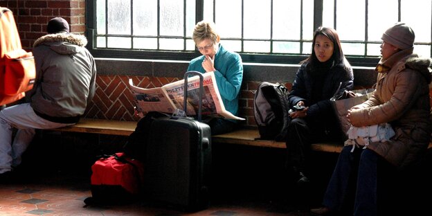 Menschen sitzen in einer Wartehalle und lesen Menschen sitzen in einer Wartehalle und lesen