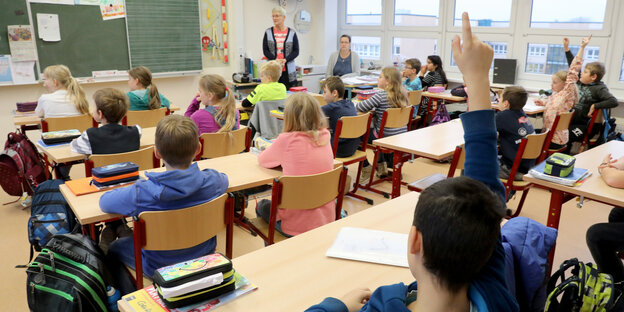 Eine Schulklasse ist zu sehen, einige Schüler melden sich Eine Schulklasse ist zu sehen, einige Schüler melden sich