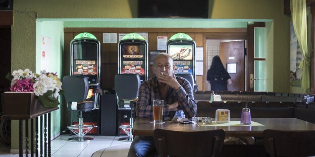 Ein Mann sitzt vor einem Getränk in einem Restaurant und zieht an einer Zigarette Ein Mann sitzt vor einem Getränk in einem Restaurant und zieht an einer Zigarette