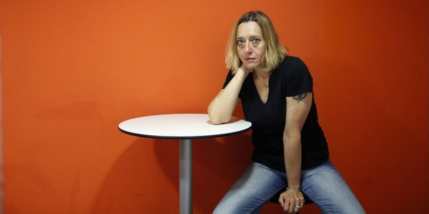 Virginie Despentes, an einem Tisch sitzend Virginie Despentes, an einem Tisch sitzend
