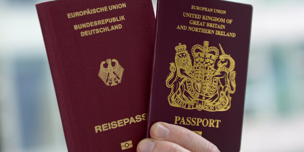 Eine Hand hält zwei Pässe fest. Einer ist der deutsche, der andere ist der britische. Eine Hand hält zwei Pässe fest. Einer ist der deutsche, der andere ist der britische.