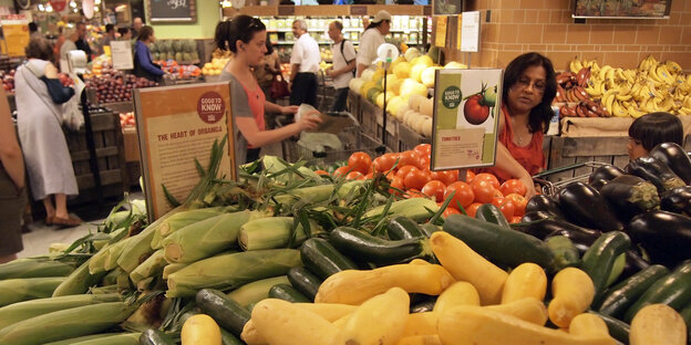 Eine handvoll Menschen sind in der Gemüseabteilung eines Supermarktes zu sehen Eine handvoll Menschen sind in der Gemüseabteilung eines Supermarktes zu sehen