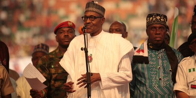 Nigerias Präsident spricht in weißem Gewand und mit Kopfbedeckung zu einer großen Menge Nigerias Präsident spricht in weißem Gewand und mit Kopfbedeckung zu einer großen Menge