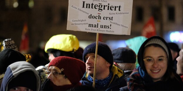 Menschen stehen zusammen. Einer hält ein Schild hoch. Menschen stehen zusammen. Einer hält ein Schild hoch.