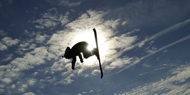 ein Skifahrer schlägt einen Salto in der Luft im Gegenlicht ein Skifahrer schlägt einen Salto in der Luft im Gegenlicht