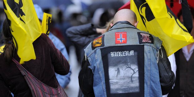 Ein glatzköpfiger Fan der norwegischen Black-Metal-Band „Burzum“ trägt eine Weste mit Motiv der Band sowie einer umgedrehten norwegischen Flagge Ein glatzköpfiger Fan der norwegischen Black-Metal-Band „Burzum“ trägt eine Weste mit Motiv der Band sowie einer umgedrehten norwegischen Flagge