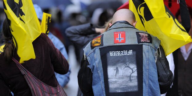 Ein glatzköpfiger Fan der norwegischen Black-Metal-Band „Burzum“ trägt eine Weste mit Motiv der Band sowie einer umgedrehten norwegischen Flagge