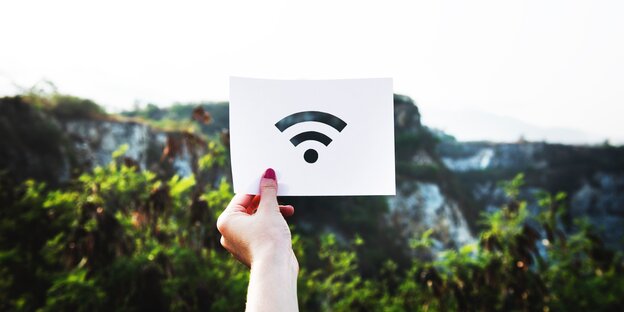 Hand hält ein Schild mit dem WLAN-Zeichen hoch Hand hält ein Schild mit dem WLAN-Zeichen hoch
