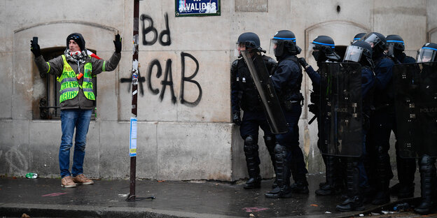 Ein Mann nimmt ein Selfie vor einem Grafitto auf, daneben stehen mehrere Polizisten Ein Mann nimmt ein Selfie vor einem Grafitto auf, daneben stehen mehrere Polizisten