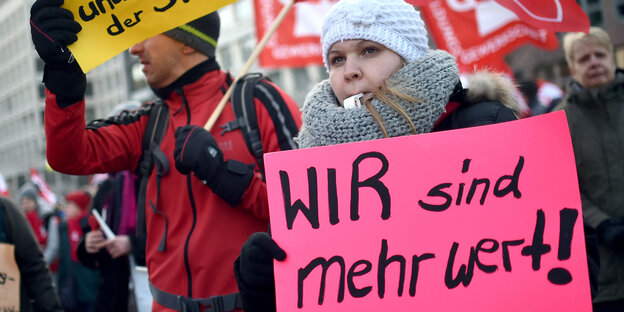 Erzieher und Sozialpädagogen streiken und zeigen Schilder mit der Aufschrift «wir werden gut bezahlt und Kinder bringt der Storch!» und «wir sind mehr wert»