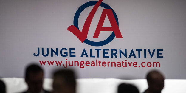 Menschen vor einer Leinwand mit einem Logo der Nachwuchsorganisation der AfD Menschen vor einer Leinwand mit einem Logo der Nachwuchsorganisation der AfD