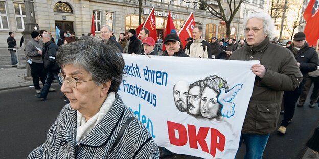 Demonstranten mit grauen Haaren tragen ein Plakat der DKP. Demonstranten mit grauen Haaren tragen ein Plakat der DKP.