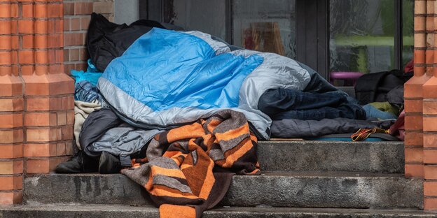 Ein Obdachloser liegt unter einer Decke in einem Eingang einer Kirche in Kreuzberg Ein Obdachloser liegt unter einer Decke in einem Eingang einer Kirche in Kreuzberg
