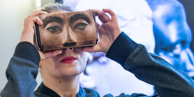 Eine Frau hält sich eine VR-Brille vor das Gesicht Eine Frau hält sich eine VR-Brille vor das Gesicht