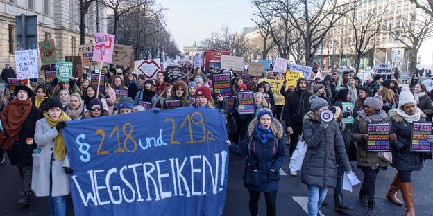 Auf einer Straße stehen zahlreiche Demonstrantinnen vor einem Transparent "Paragraf 218 und 219a wegstreiken!" Auf einer Straße stehen zahlreiche Demonstrantinnen vor einem Transparent "Paragraf 218 und 219a wegstreiken!"