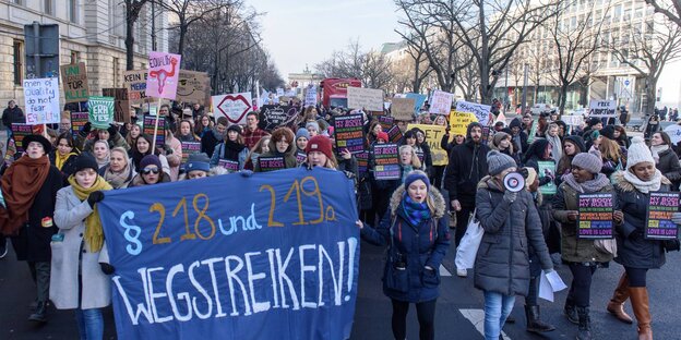 Auf einer Straße stehen zahlreiche Demonstrantinnen vor einem Transparent "Paragraf 218 und 219a wegstreiken!"