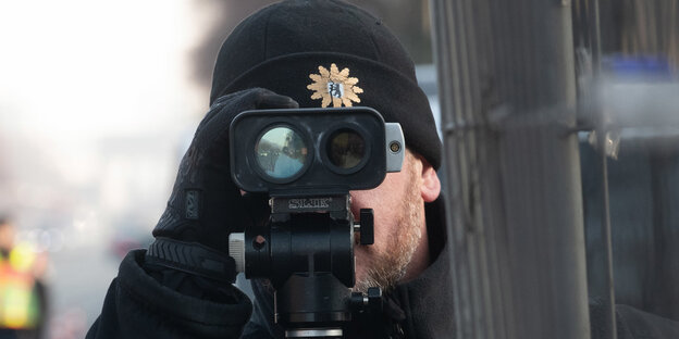 Ein Polizist guckt durch ein Fernglas Ein Polizist guckt durch ein Fernglas