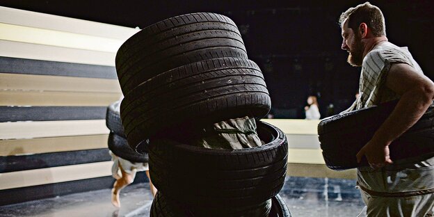 In Autoreifen gehüllte Schauspieler gehen über eine Bühne. In Autoreifen gehüllte Schauspieler gehen über eine Bühne.