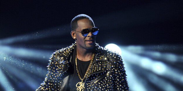 R. Kelly im Bühnenoutfit vor Scheinwerferlichtkegeln R. Kelly im Bühnenoutfit vor Scheinwerferlichtkegeln