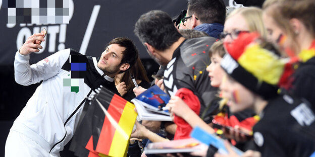 Ein Handballspieler macht ein Selfie vor Fans Ein Handballspieler macht ein Selfie vor Fans