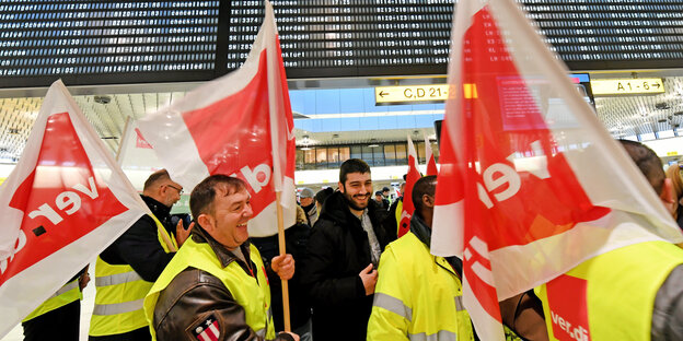 Viele Menschen in gelben Westen schwenken Fahnen an einem Flughafen Viele Menschen in gelben Westen schwenken Fahnen an einem Flughafen