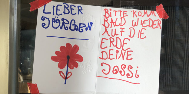 Eine Zettel mit der Aufschrift "Lieber Jürgen, bitte komm' bald wieder auf die Erde". Eine Zettel mit der Aufschrift "Lieber Jürgen, bitte komm' bald wieder auf die Erde".
