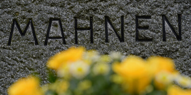 Gedenktafel mit Blumen und dem Wort "Mahnen" Gedenktafel mit Blumen und dem Wort "Mahnen"