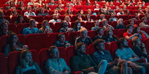 Menschen sitzen im Kinosaal und schauen auf die Leinwand