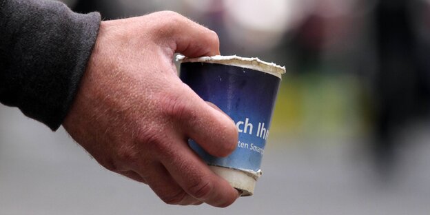Eine Hand hält einen Pappbecher Eine Hand hält einen Pappbecher