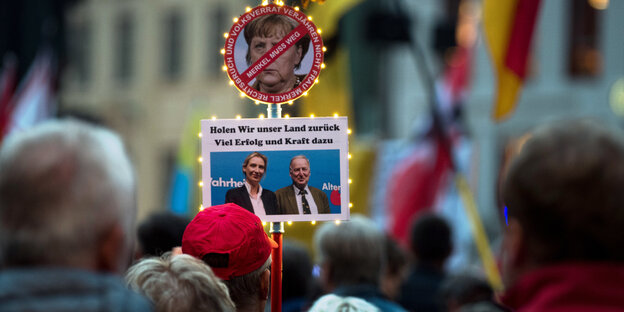 Demonstranten haben an einem Stock ein "Merkel-muss-weg"-Schild sowie ein Foto von Alice Weidel und Alexander Gauland befestigt Demonstranten haben an einem Stock ein "Merkel-muss-weg"-Schild sowie ein Foto von Alice Weidel und Alexander Gauland befestigt