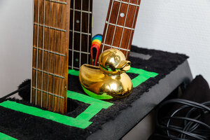 Eine goldene Badeente steht zwischen Gitarrenhälsen Eine goldene Badeente steht zwischen Gitarrenhälsen