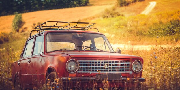 Ein Oldtimer-Auto steht inmitten eines Feldes Ein Oldtimer-Auto steht inmitten eines Feldes