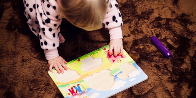 Ein Kind spielt mit einem Puzzle mit sechs Teilen Ein Kind spielt mit einem Puzzle mit sechs Teilen