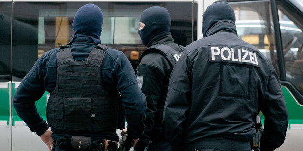 Drei Polizisten stehen mit dem Rücken zum Betrachter Drei Polizisten stehen mit dem Rücken zum Betrachter