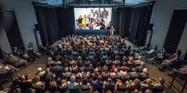 Saal von oben fotografiert mit vielen Sitzreihen voller Menschen Saal von oben fotografiert mit vielen Sitzreihen voller Menschen