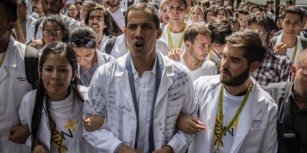 uan Guaido (Mitte), selbst ernannter Interimspräsidenten, marschiert in weißem Kittel mit Personal des Gesundheitswesens, Ärzten und Medizinstudenten gegen die Regierung von Präsident Maduro. uan Guaido (Mitte), selbst ernannter Interimspräsidenten, marschiert in weißem Kittel mit Personal des Gesundheitswesens, Ärzten und Medizinstudenten gegen die Regierung von Präsident Maduro.