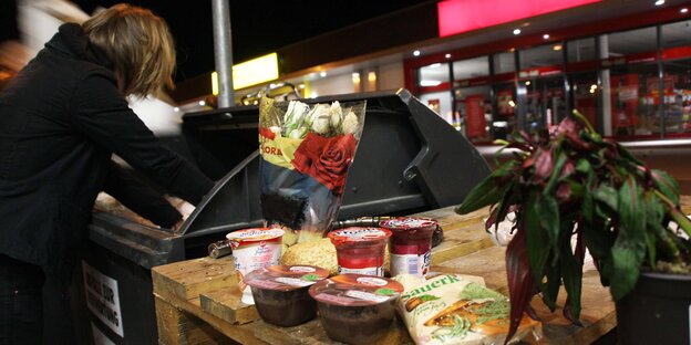 Frau beugt sich über Container, vorn stehen Puddingbecher Frau beugt sich über Container, vorn stehen Puddingbecher