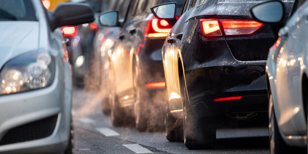 Eine von Autos verstopfte Straße, aus den Auspuffen strömen Abgase Eine von Autos verstopfte Straße, aus den Auspuffen strömen Abgase