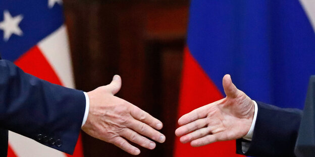 US Präsident Donald Trump (l) und der russische Präsident Wladimir Putin (r) geben sich die Hand. Im Hintergrund sind die Flaggen der USA und Russlands zu sehen US Präsident Donald Trump (l) und der russische Präsident Wladimir Putin (r) geben sich die Hand. Im Hintergrund sind die Flaggen der USA und Russlands zu sehen