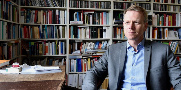 ein Mann sitzt vor einer Bücherwand ein Mann sitzt vor einer Bücherwand