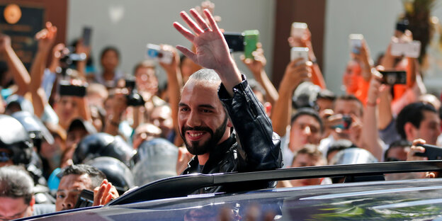 Nayib Bukele lehnt sich aus einem auto und winkt. Nayib Bukele lehnt sich aus einem auto und winkt.